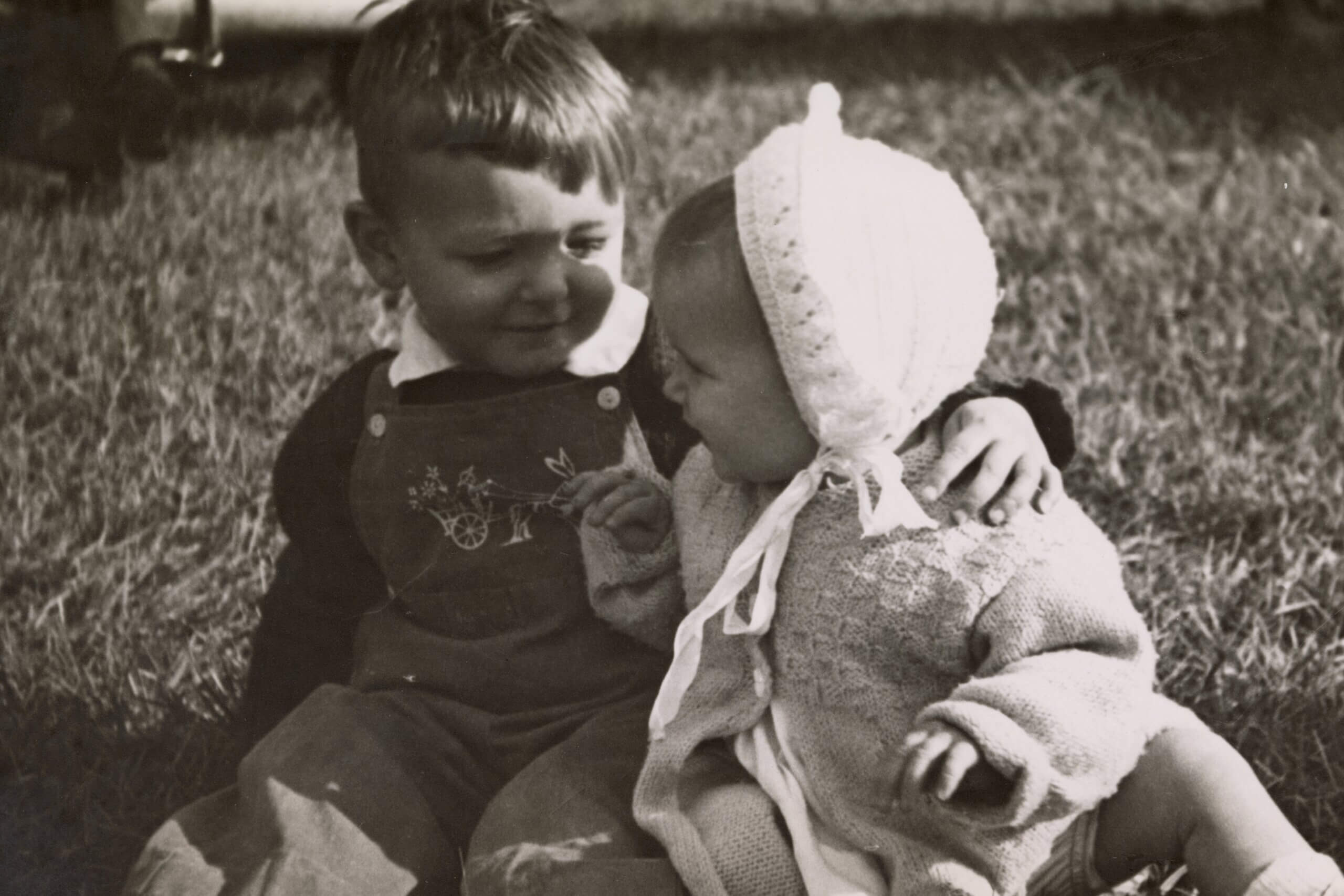 Black-and-white photo of two young kids sitting in a field