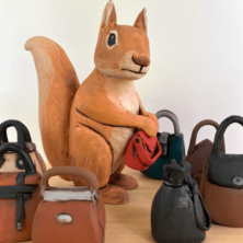 Figurine of a squirrel with a tiny bag.