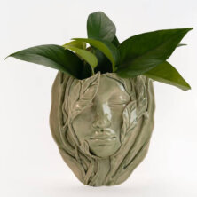 Green clay bust of a person with leafs coming out of their head